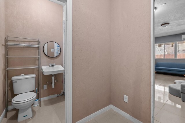 bathroom with tile patterned flooring, baseboards, a sink, and toilet