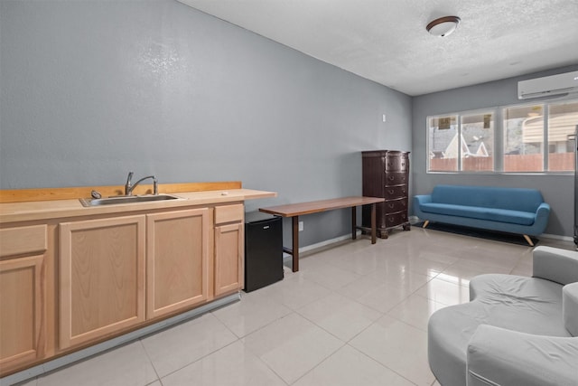 living room with light tile patterned floors, baseboards, a textured ceiling, and a wall mounted air conditioner