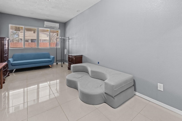 sitting room featuring a textured ceiling, a wall unit AC, baseboards, and tile patterned floors