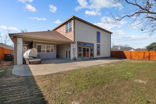 back of house with central air condition unit, stucco siding, a patio area, fence, and a lawn