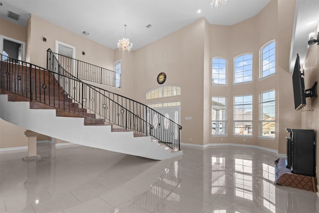 foyer with a high ceiling, baseboards, visible vents, and stairs