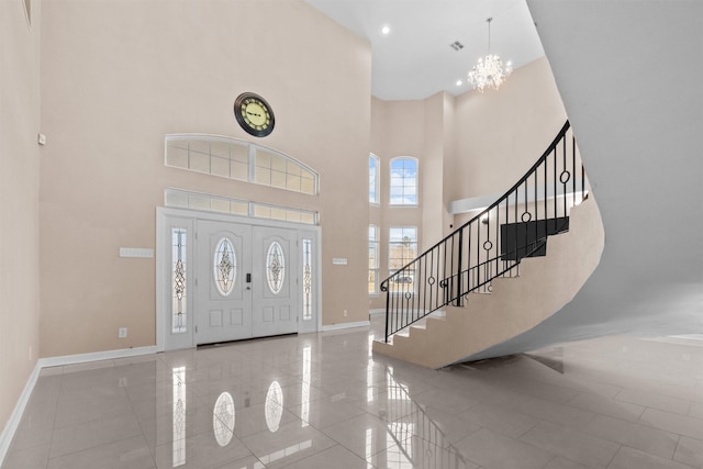 entryway featuring an inviting chandelier, a towering ceiling, visible vents, stairs, and baseboards