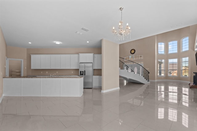 interior space with baseboards, an inviting chandelier, light tile patterned floors, stairs, and visible vents