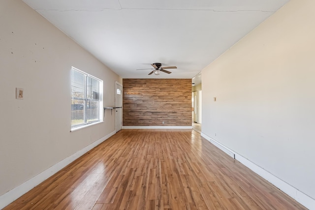 empty room featuring light hardwood / wood-style floors, ceiling fan, and wood walls