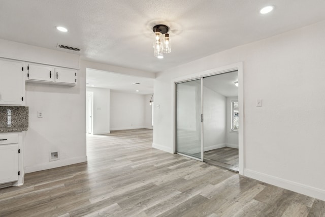 interior space with decorative backsplash, light hardwood / wood-style floors, and white cabinets