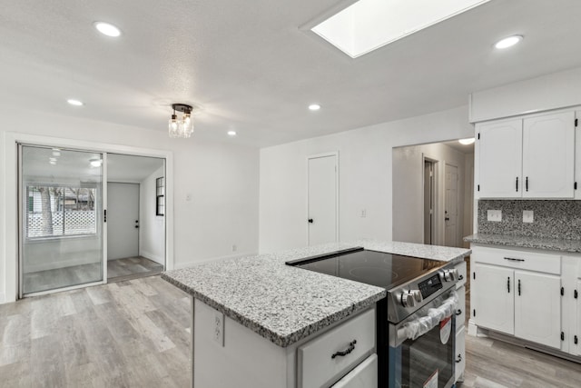 kitchen with stainless steel range with electric cooktop, tasteful backsplash, light wood-type flooring, a kitchen island, and white cabinets