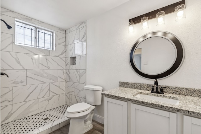 bathroom featuring vanity, hardwood / wood-style floors, toilet, and tiled shower