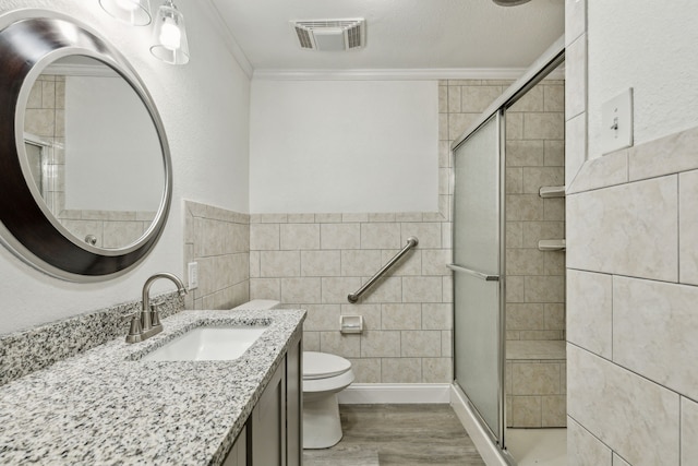 bathroom with tile walls, hardwood / wood-style flooring, ornamental molding, walk in shower, and toilet