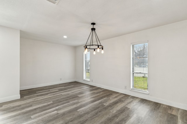 unfurnished dining area featuring an inviting chandelier and wood-type flooring