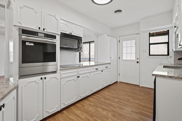 kitchen with white cabinets, light stone countertops, and black appliances