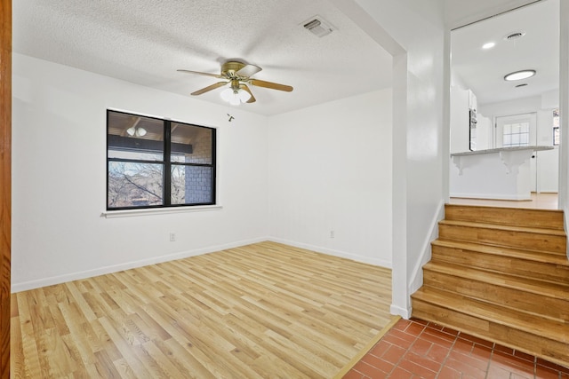 unfurnished room with ceiling fan, light hardwood / wood-style floors, and a textured ceiling