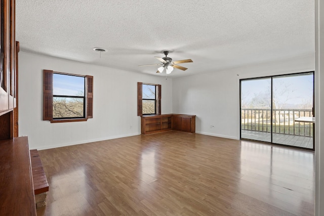 unfurnished living room with ceiling fan, a textured ceiling, and light wood-type flooring