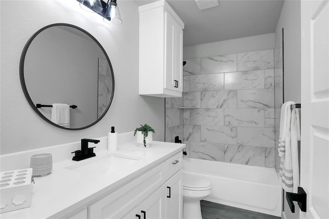 full bathroom featuring tiled shower / bath, vanity, and toilet