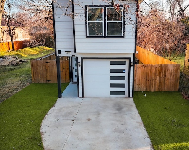 view of front of house featuring driveway, an attached garage, fence, and a front yard