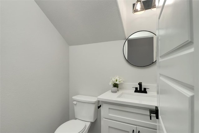 bathroom with lofted ceiling, vanity, and toilet