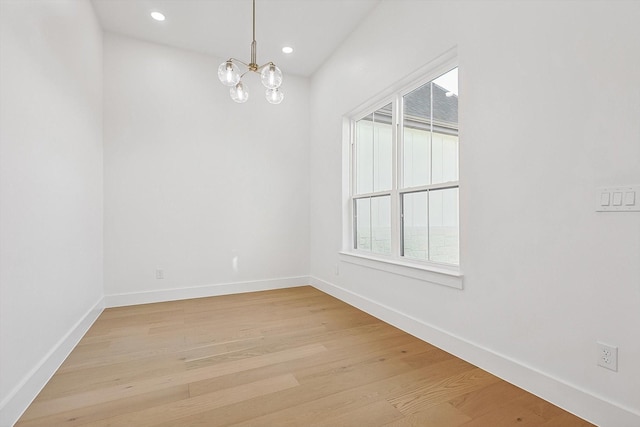 empty room with plenty of natural light, a chandelier, and light hardwood / wood-style flooring