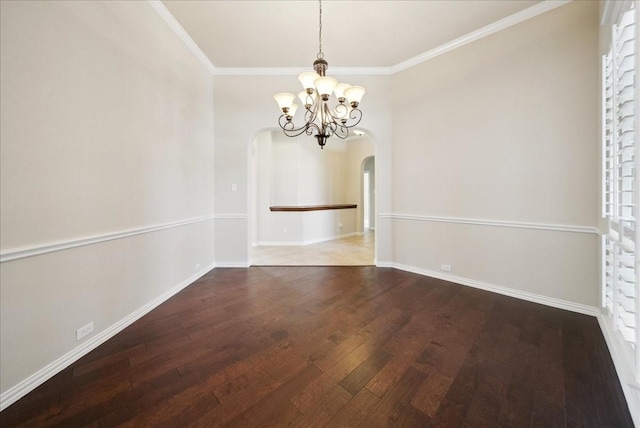 unfurnished room featuring arched walkways, crown molding, an inviting chandelier, wood finished floors, and baseboards