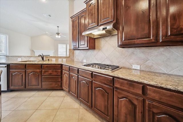 kitchen with sink, decorative backsplash, stainless steel gas cooktop, light tile patterned floors, and light stone counters