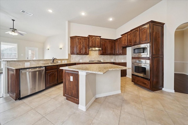 kitchen featuring visible vents, arched walkways, appliances with stainless steel finishes, under cabinet range hood, and a sink