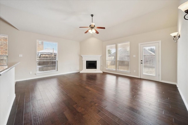 unfurnished living room featuring vaulted ceiling, dark wood-type flooring, and a wealth of natural light