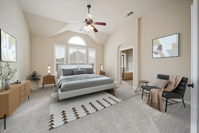 bedroom with light carpet, connected bathroom, vaulted ceiling, and ceiling fan