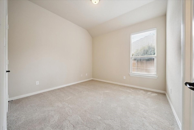 carpeted empty room featuring vaulted ceiling