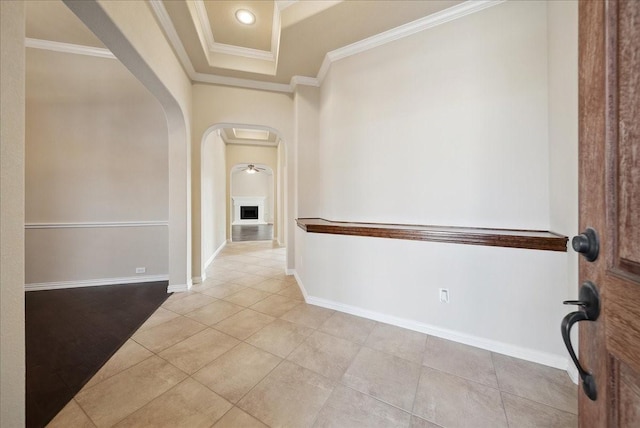 hallway featuring crown molding, light tile patterned flooring, and a tray ceiling