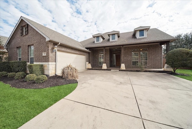 view of front facade featuring an attached garage, driveway, a front yard, and brick siding