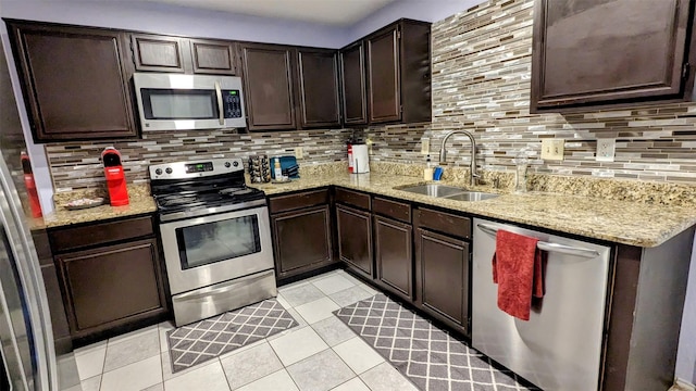 kitchen with sink, dark brown cabinets, light tile patterned floors, appliances with stainless steel finishes, and backsplash