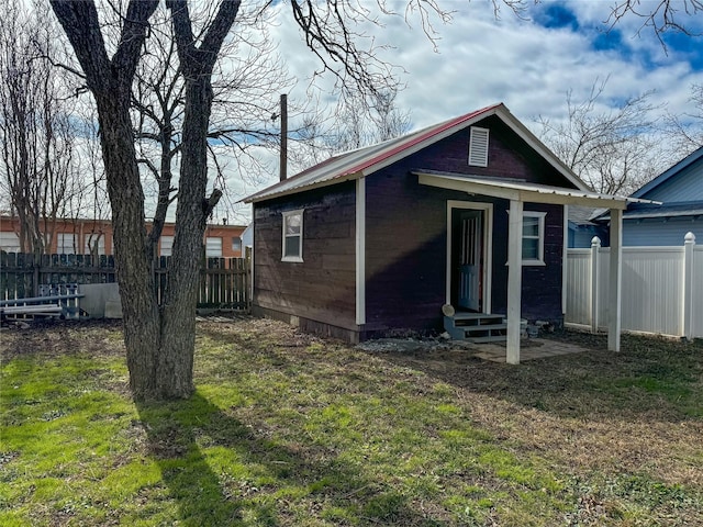 rear view of property featuring a yard and an outdoor structure