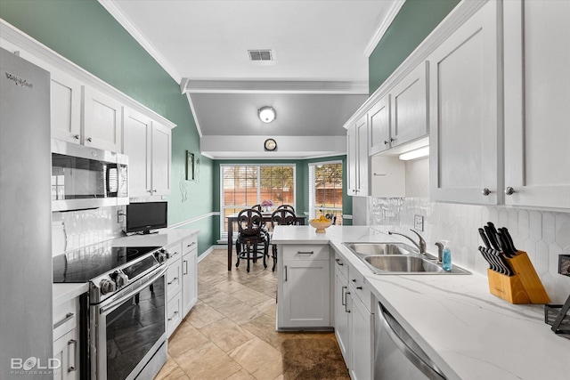 kitchen with lofted ceiling, sink, white cabinetry, ornamental molding, and appliances with stainless steel finishes