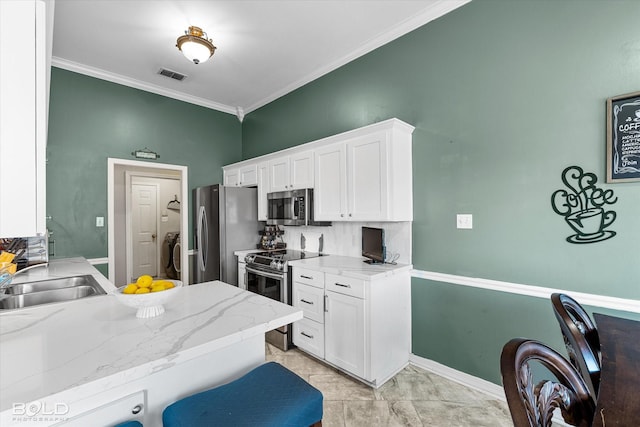 kitchen with sink, white cabinetry, stainless steel appliances, a kitchen breakfast bar, and ornamental molding