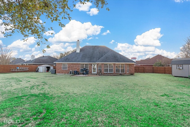 back of property with a shed, a lawn, and a patio