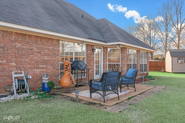 rear view of house featuring a yard, a storage unit, and a patio