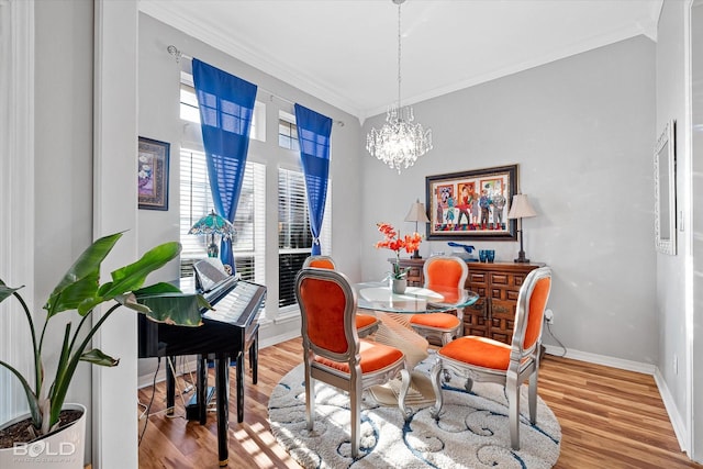 dining room with wood-type flooring, ornamental molding, and an inviting chandelier