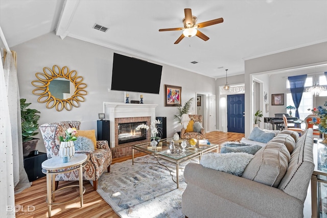 living room featuring crown molding, ceiling fan, a brick fireplace, and light hardwood / wood-style flooring