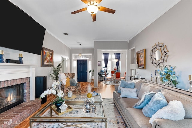 living room featuring crown molding, ceiling fan, a brick fireplace, and hardwood / wood-style flooring