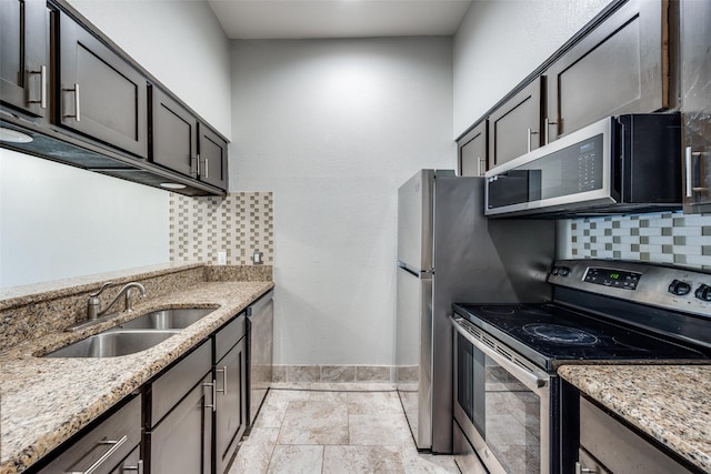 kitchen featuring sink, stainless steel appliances, tasteful backsplash, dark brown cabinetry, and light stone countertops