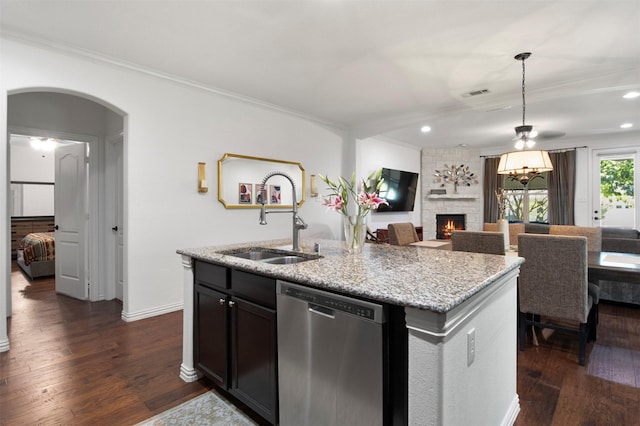 kitchen featuring sink, dishwasher, dark hardwood / wood-style floors, light stone counters, and an island with sink