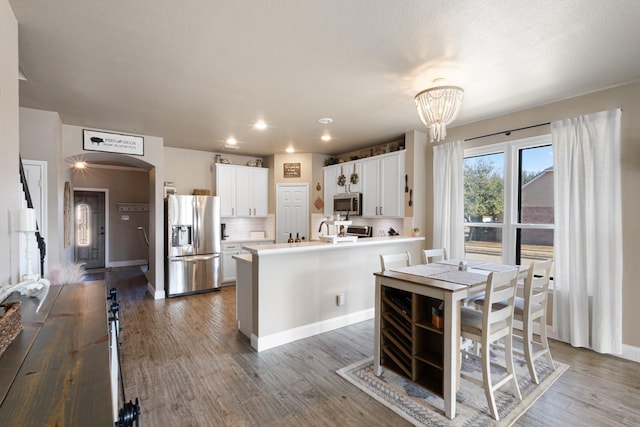 kitchen featuring a chandelier, a center island, appliances with stainless steel finishes, hardwood / wood-style floors, and white cabinets