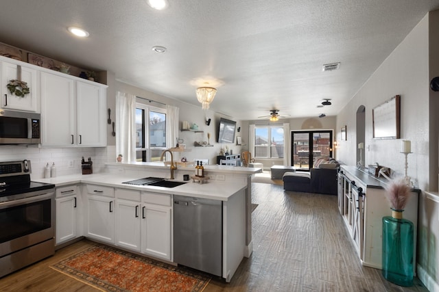 kitchen featuring sink, stainless steel appliances, white cabinets, dark hardwood / wood-style flooring, and kitchen peninsula