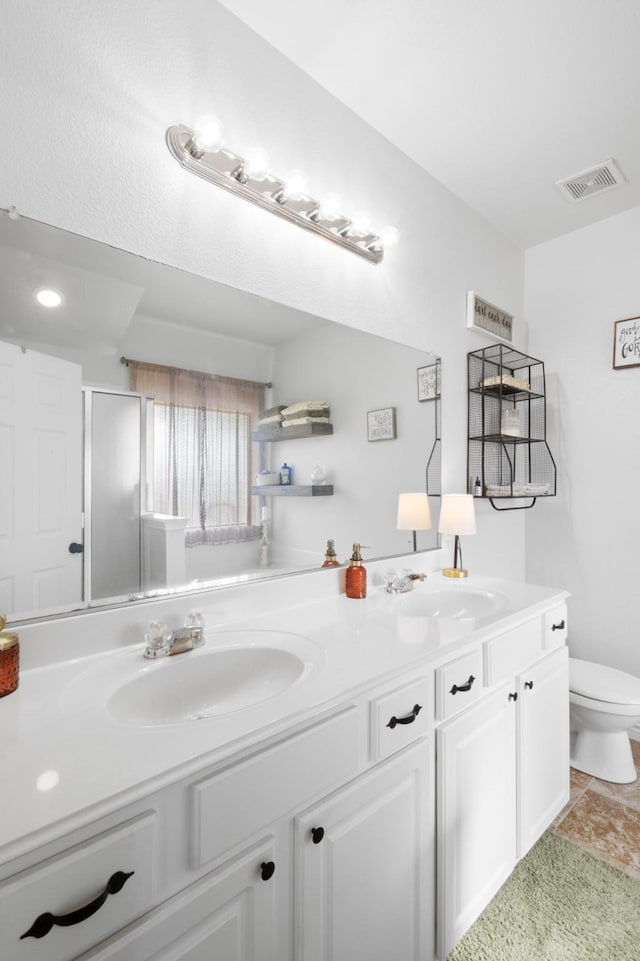 bathroom with vanity, a shower with shower door, and toilet