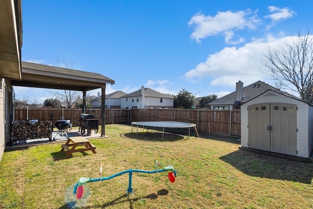 view of yard with a trampoline and a storage unit