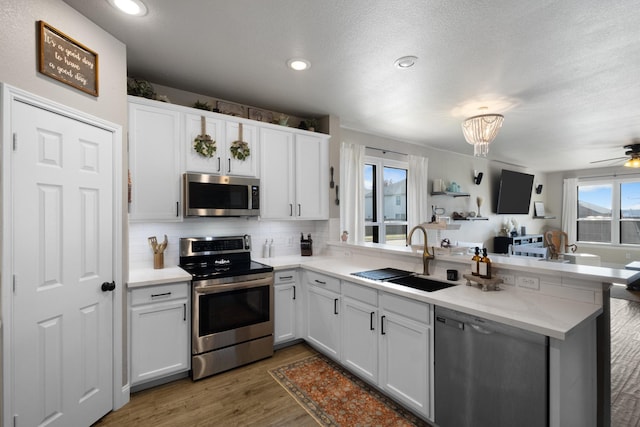 kitchen with stainless steel appliances, sink, white cabinets, and kitchen peninsula