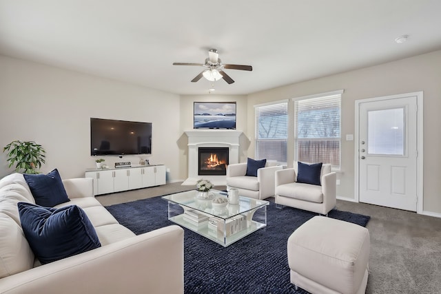 living area with carpet floors, ceiling fan, baseboards, and a glass covered fireplace