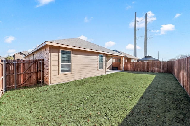 rear view of house with brick siding, a lawn, a patio area, and a fenced backyard