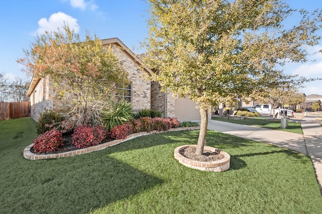 obstructed view of property with concrete driveway, brick siding, a front yard, and fence