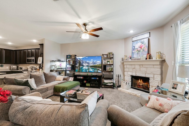 living room featuring light carpet, sink, a fireplace, and ceiling fan