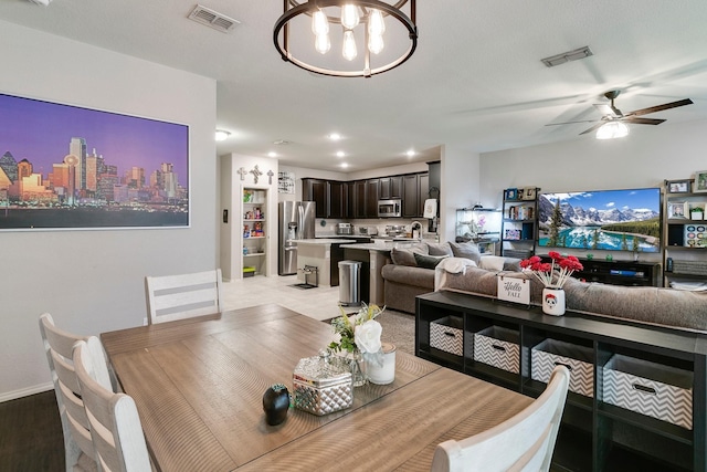 dining space with ceiling fan with notable chandelier