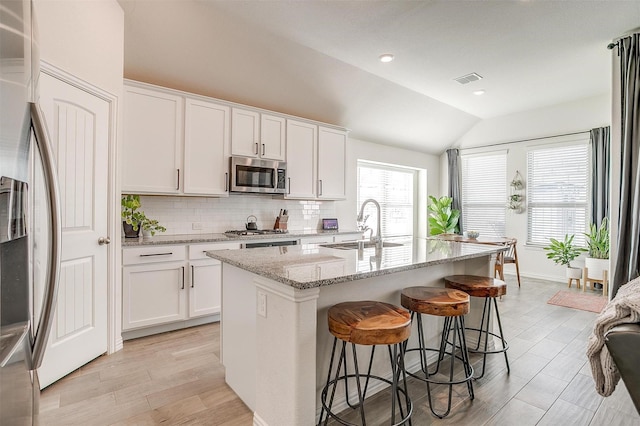 kitchen featuring a kitchen island with sink, white cabinets, and appliances with stainless steel finishes